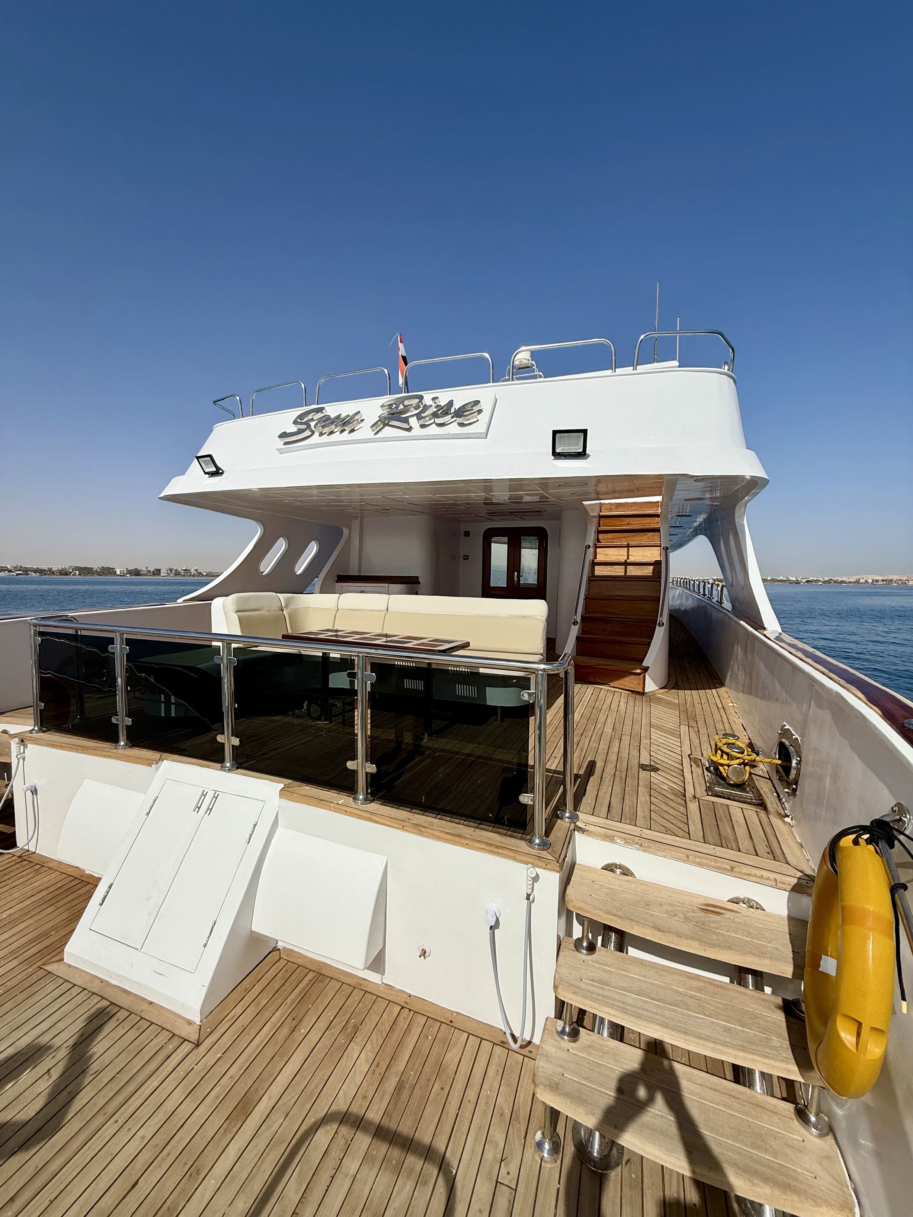 Teak aft deck of the Sun Rise yacht with corner sofa and dining table